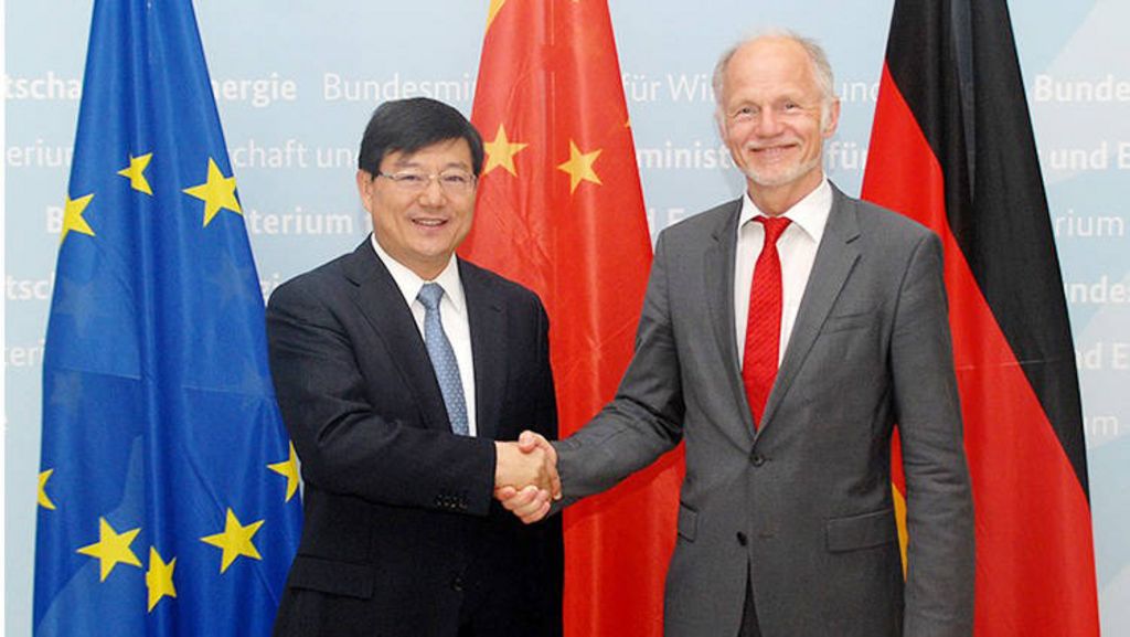 NDRC Vice Director Hu Zucai shaking hands with former State Secretary Rainer Baake in front of the flags of the European Union, China and Germany.